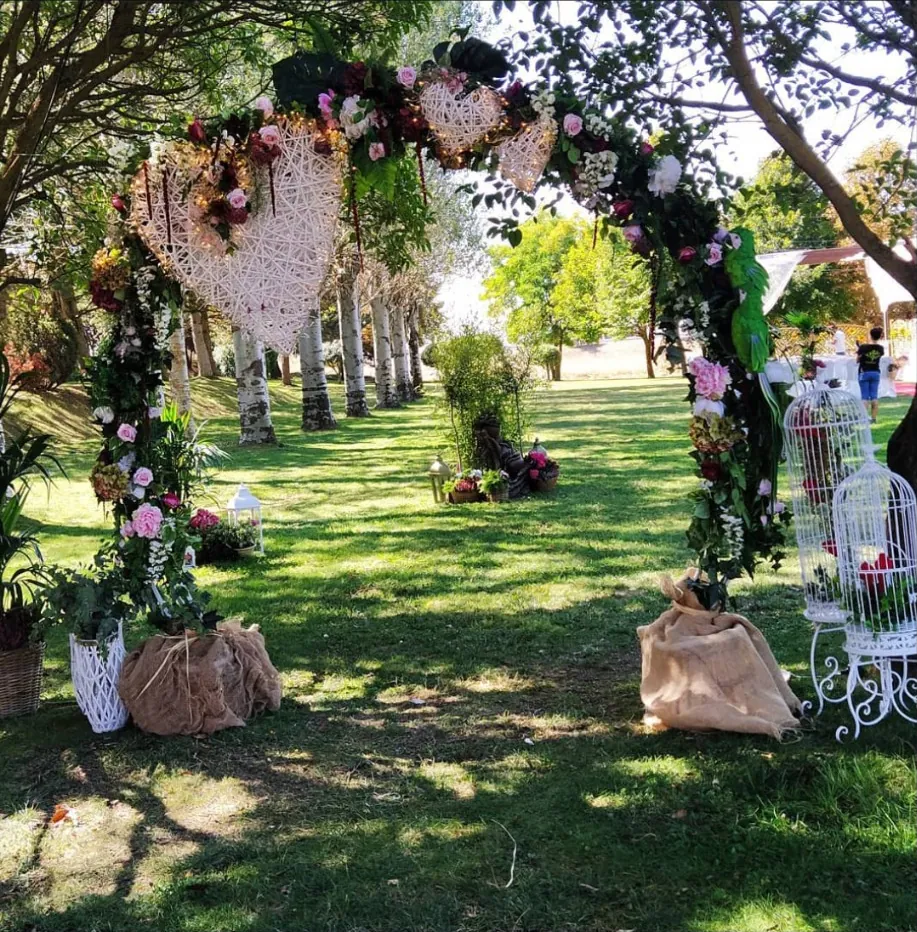Arco floral con corazones de mimbre y flores para boda en jardín de Burgos